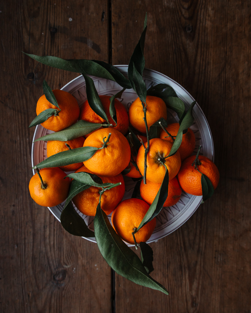 Clementines and green leaves on a rustic wooden table